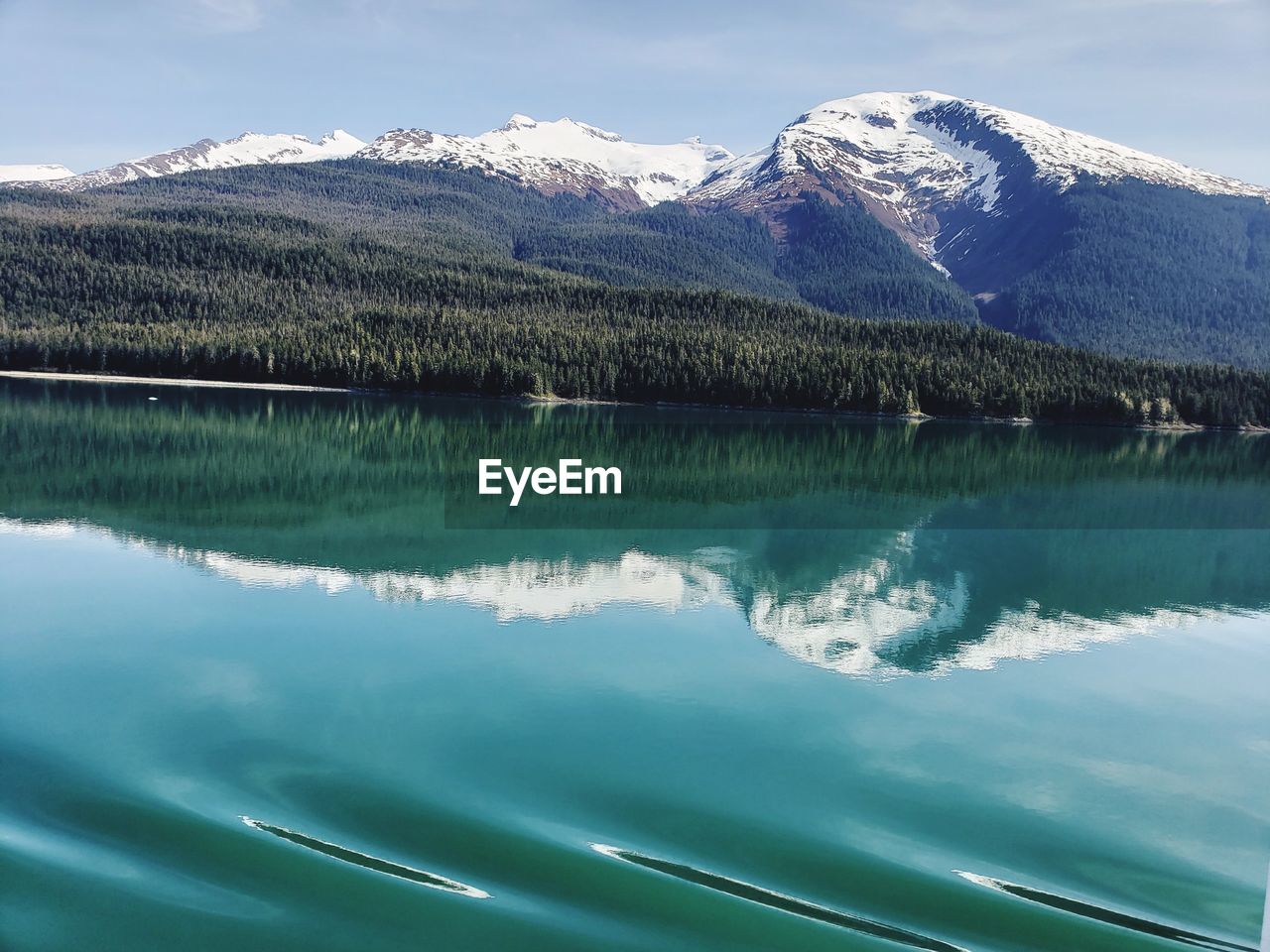 Scenic view of lake by snowcapped mountains against sky