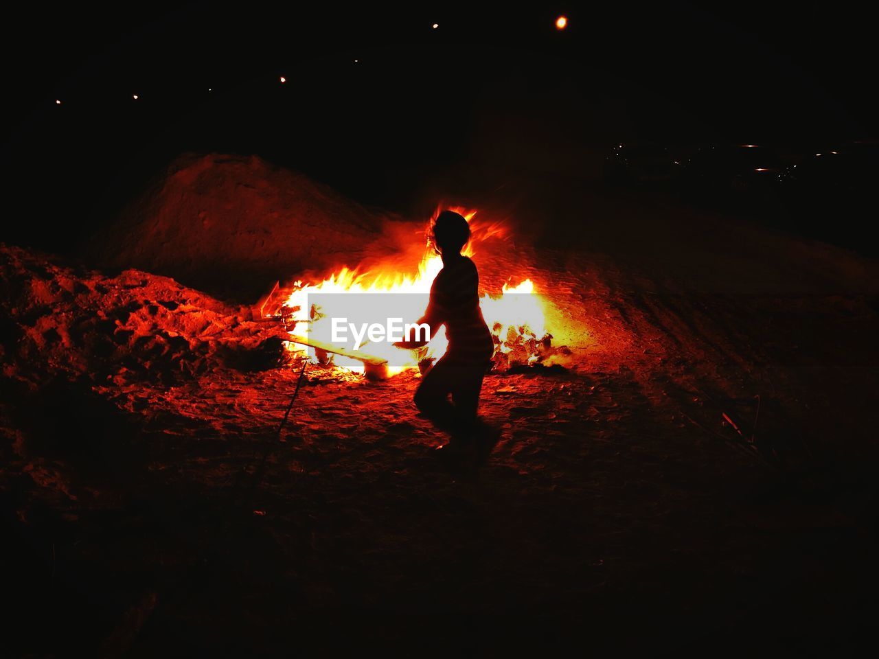 Man standing in front of bonfire at night