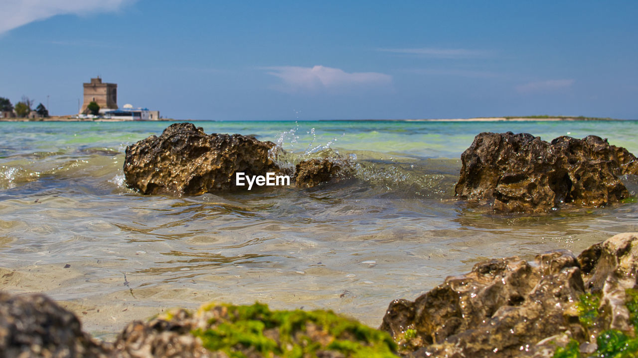 Rock formation on beach against sky