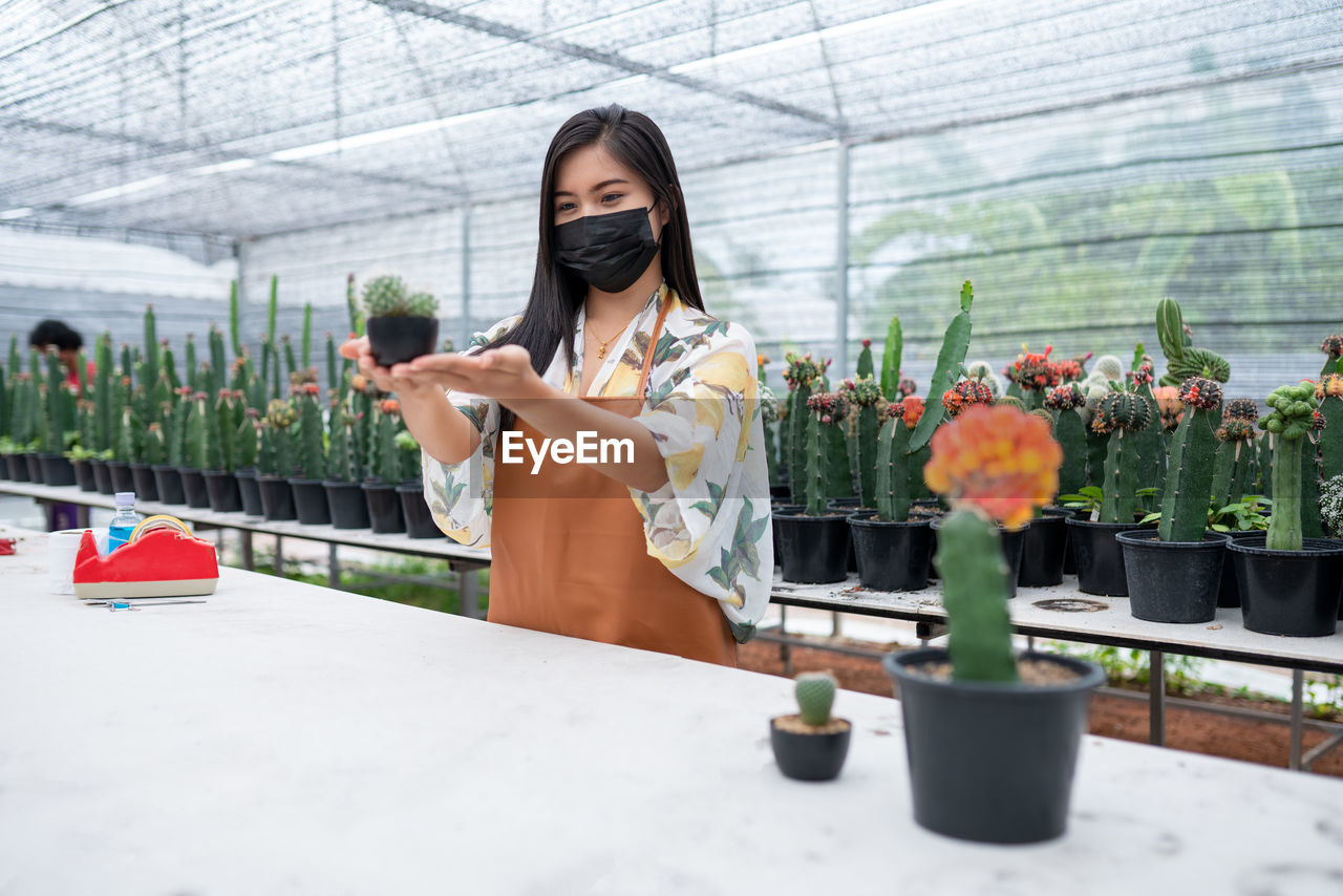 portrait of young woman standing by plants