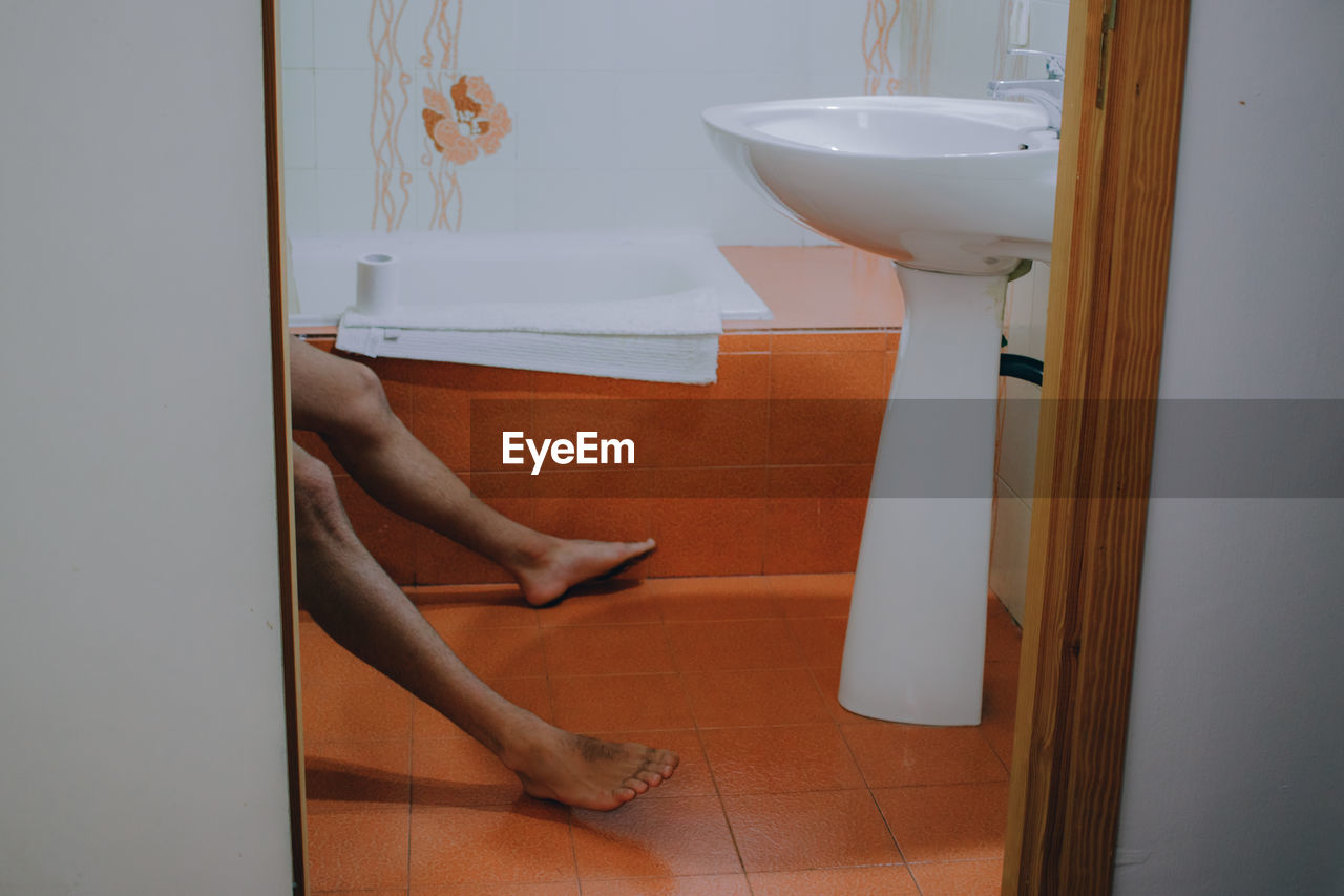 Low section of person in bathroom at home