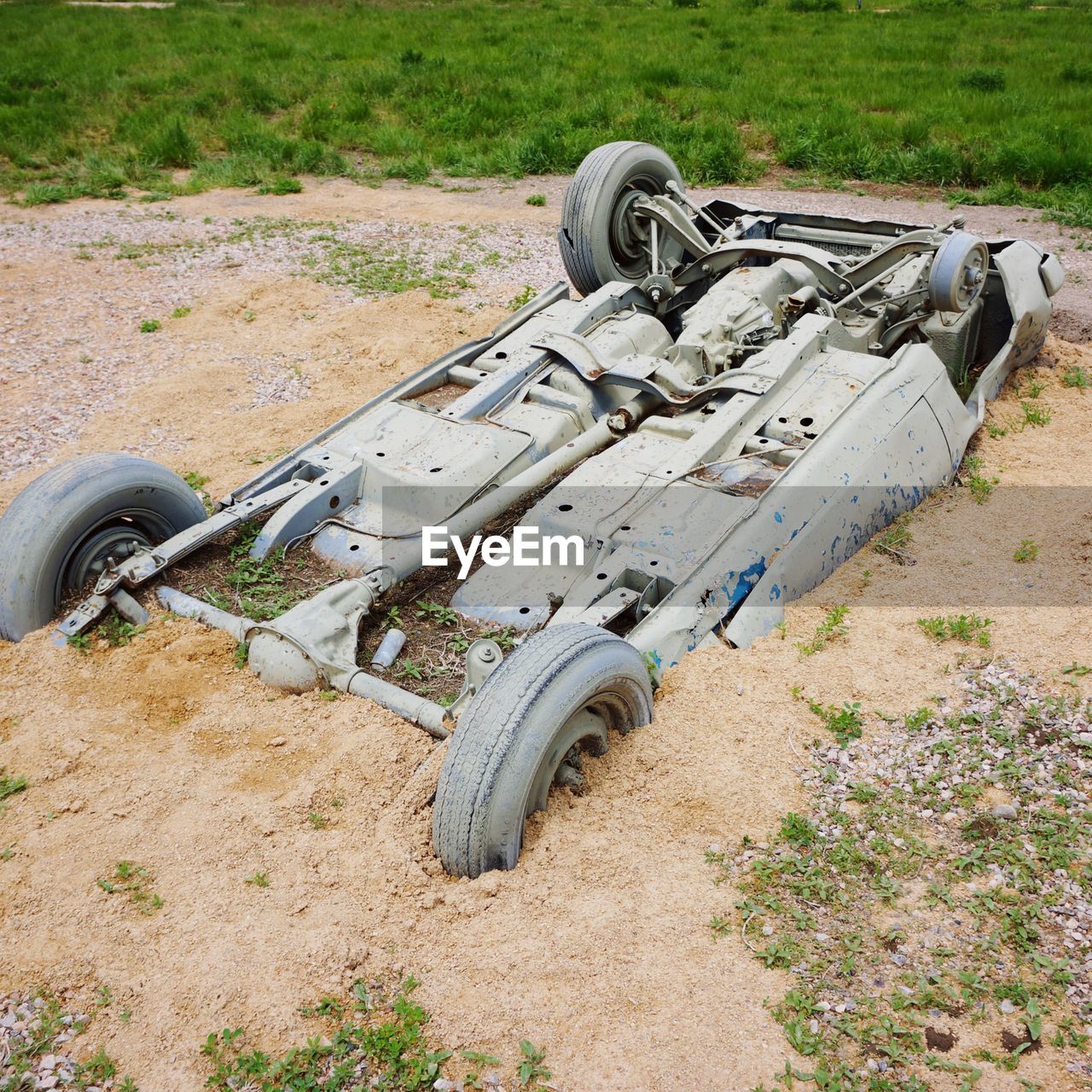 Abandoned upside down car half buried in sand