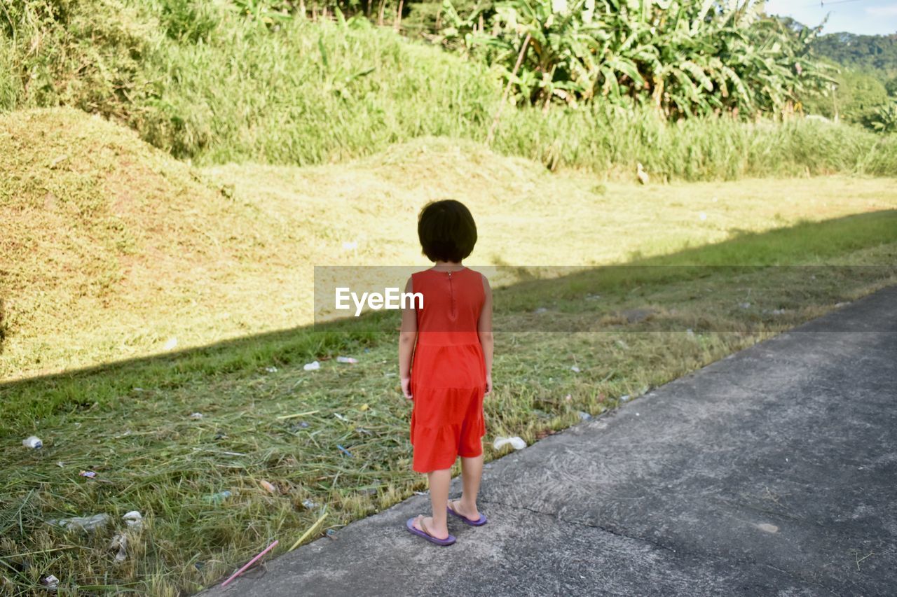FULL LENGTH REAR VIEW OF A MAN WALKING ON GRASS