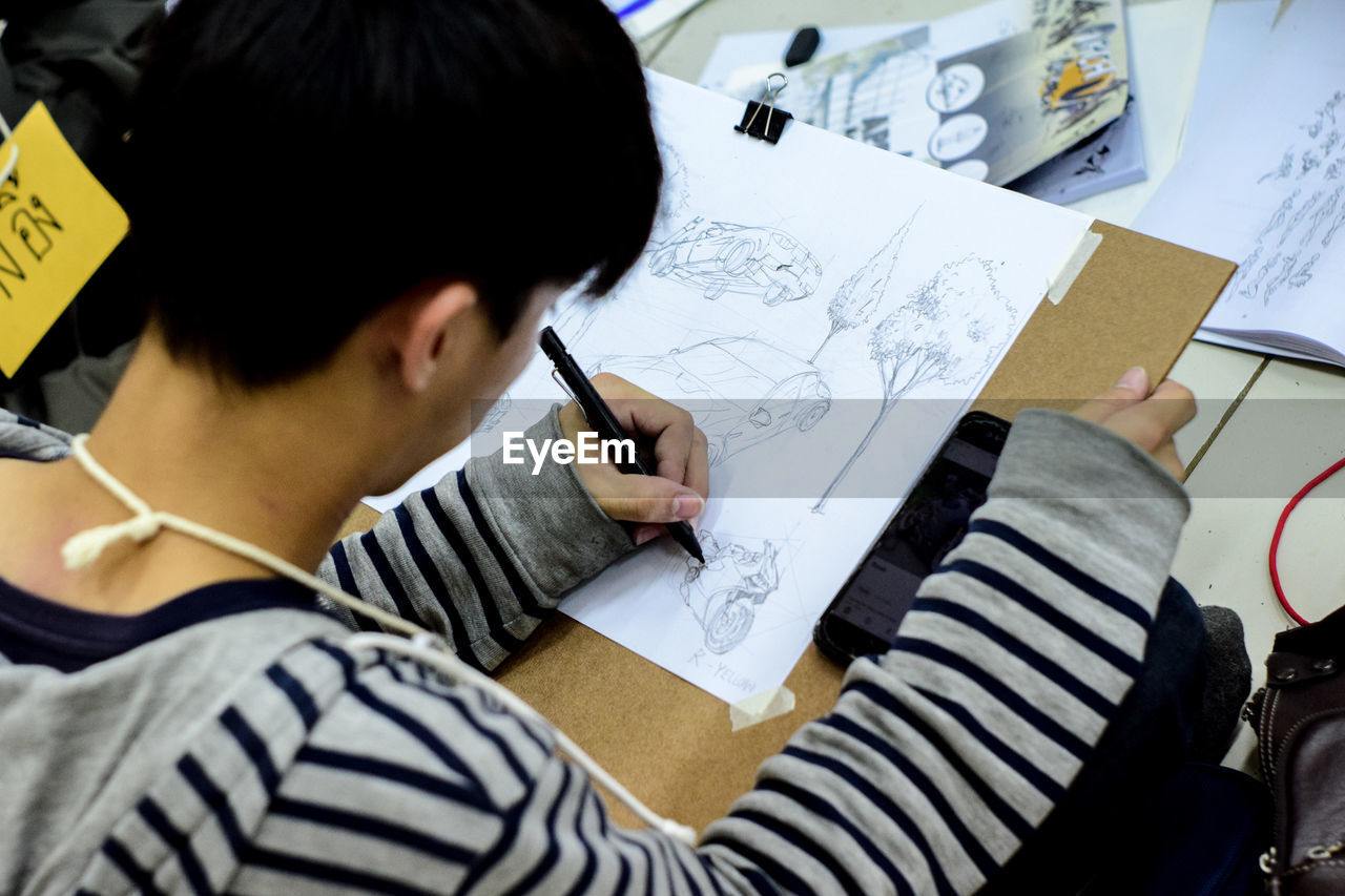 High angle view of teenage boy drawing on paper