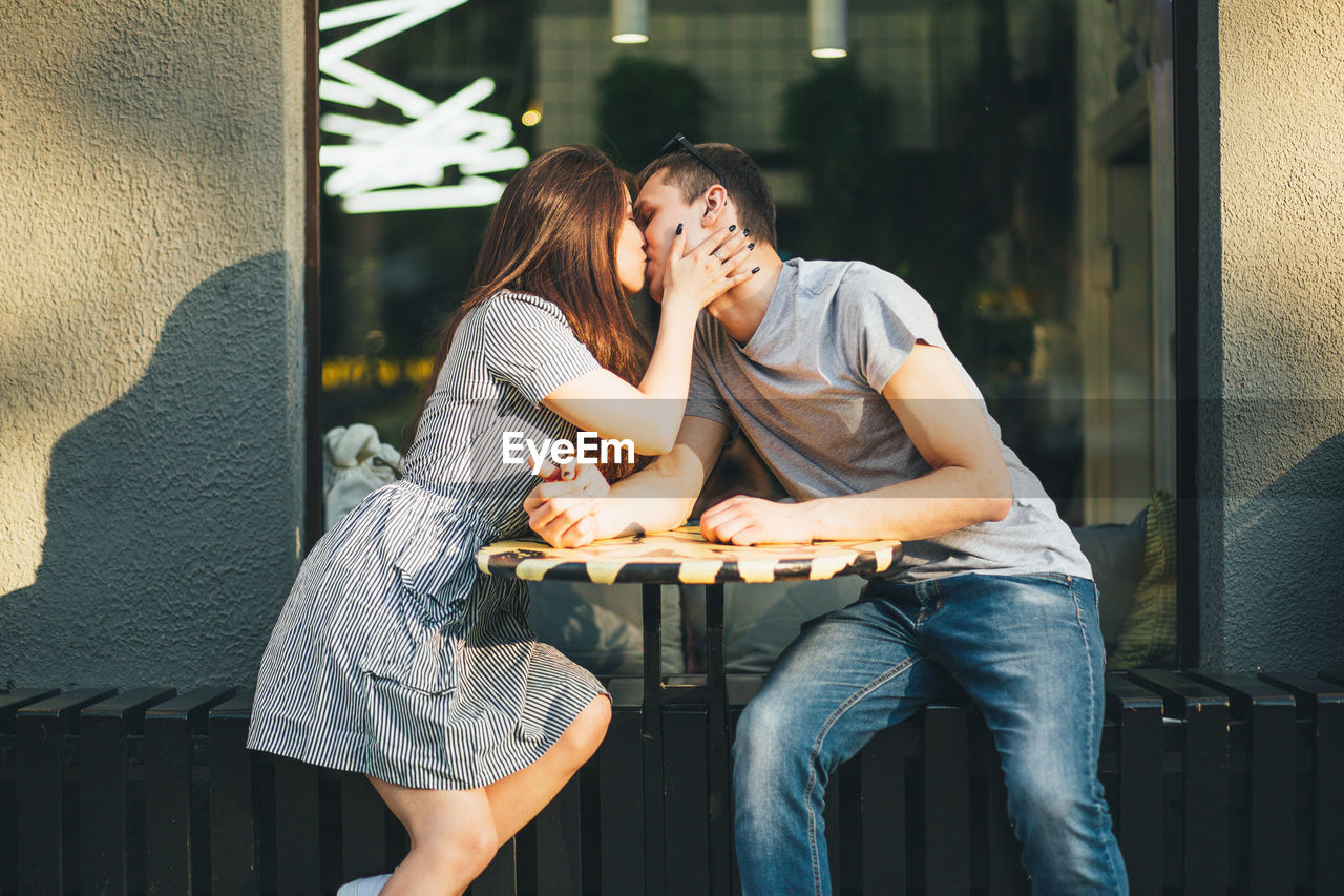 Young couple kissing while sitting at sidewalk cafe