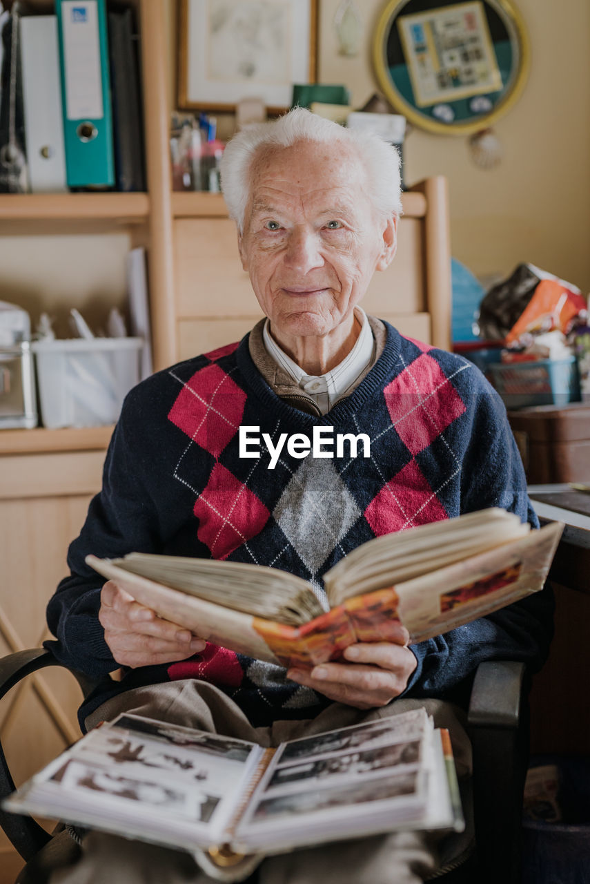 Portrait of senior man looking at photo album at home