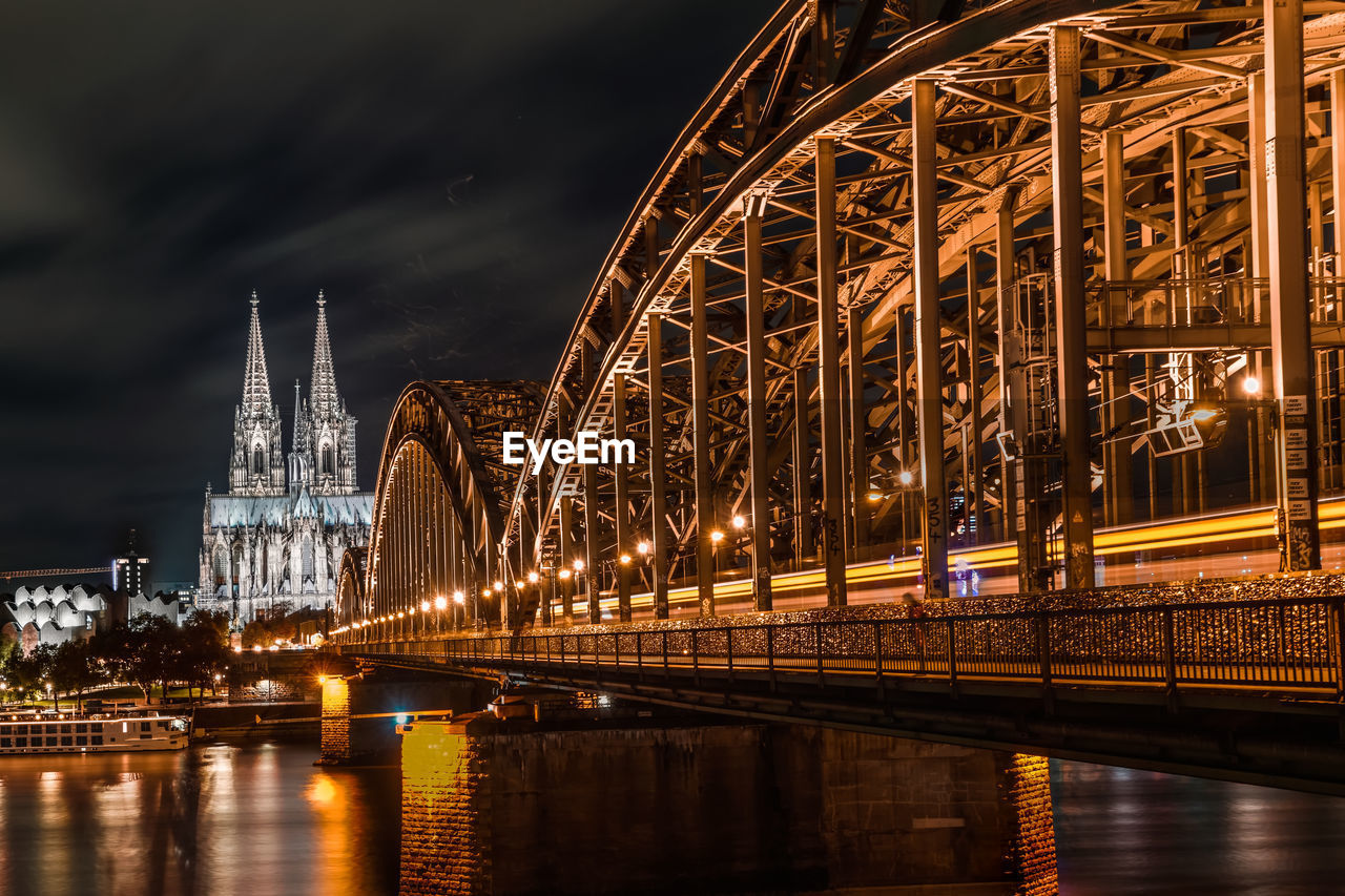 Illuminated bridge over river at night