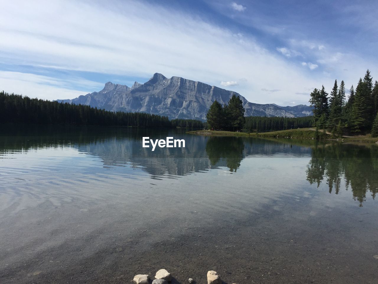 Mountain by calm lake against cloudy sky