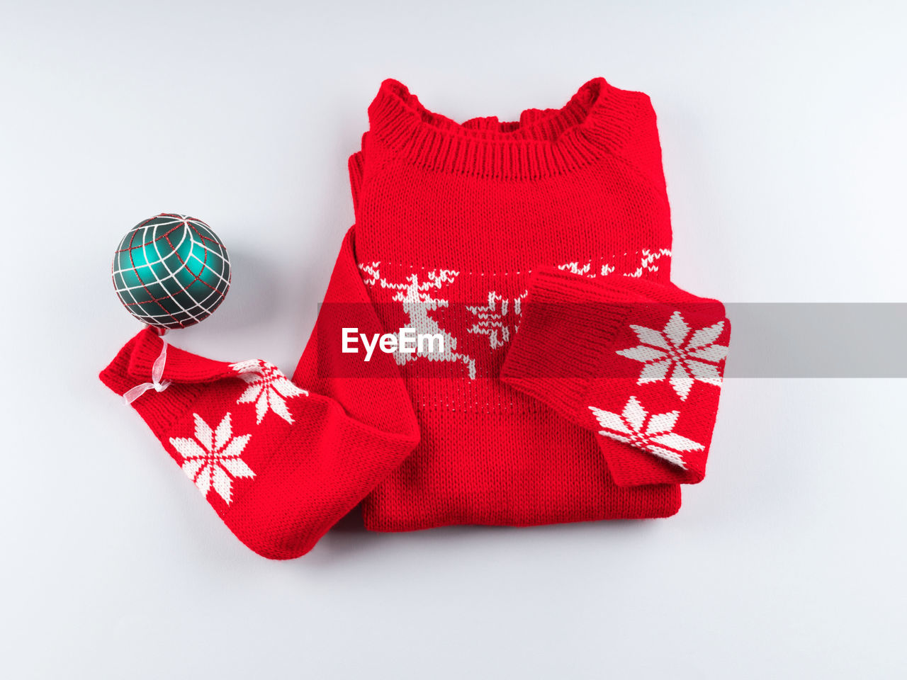 Red ugly christmas sweater with green ornament on gray background. minimal festive flat lay