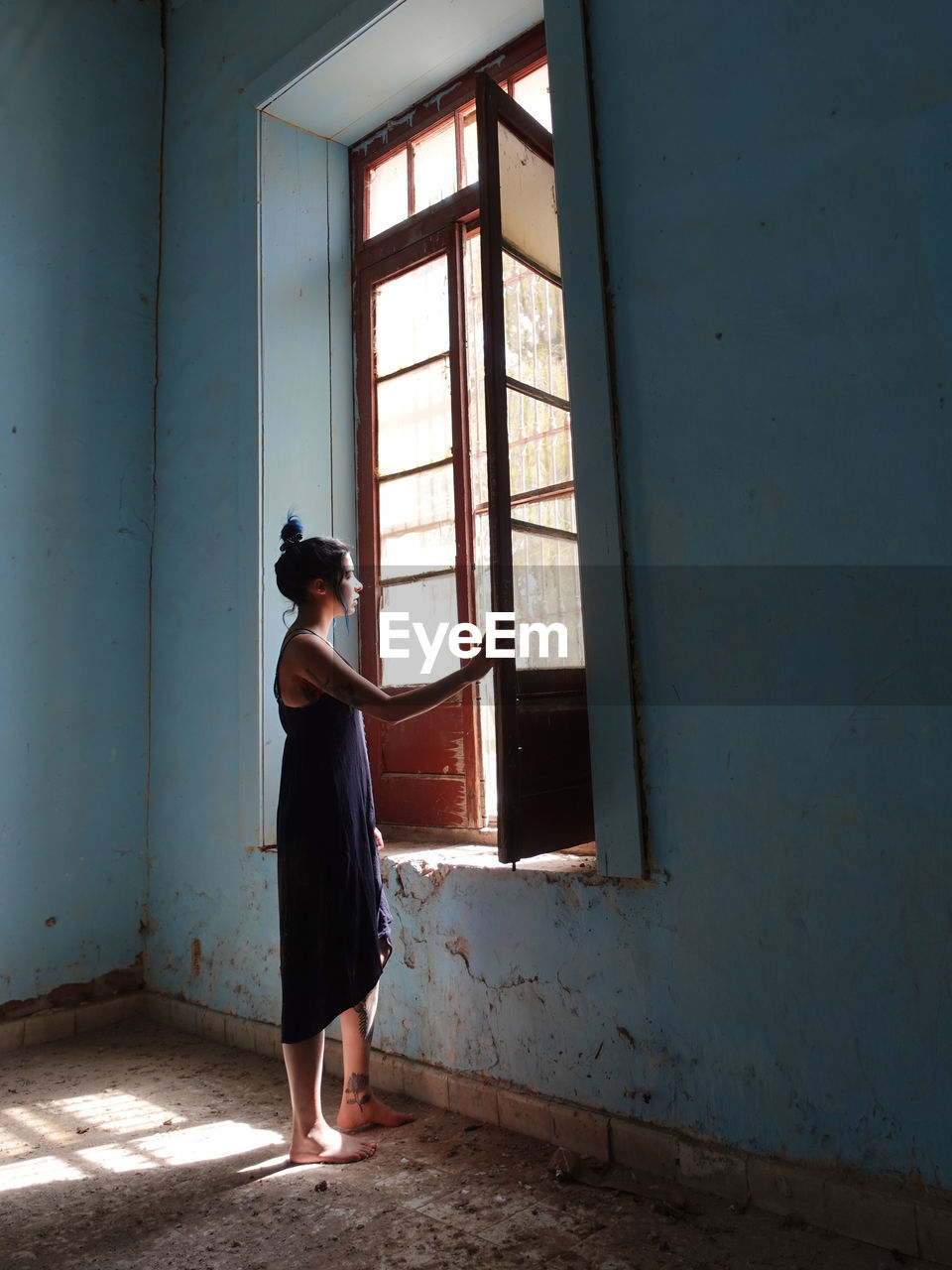 Side view of young woman standing against wall