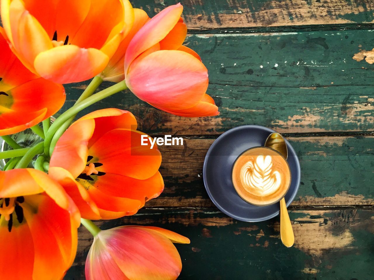 Close-up of orange tulip flowers and coffee cup