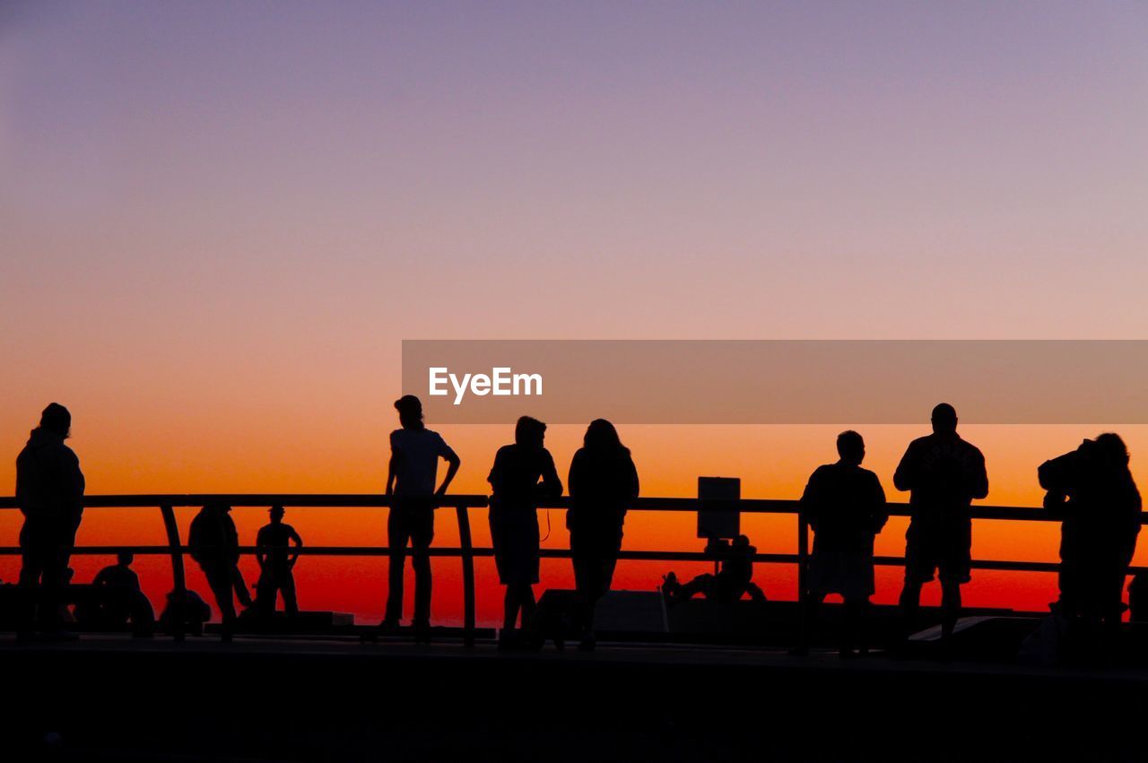 Silhouette people at observation point against sky during sunset