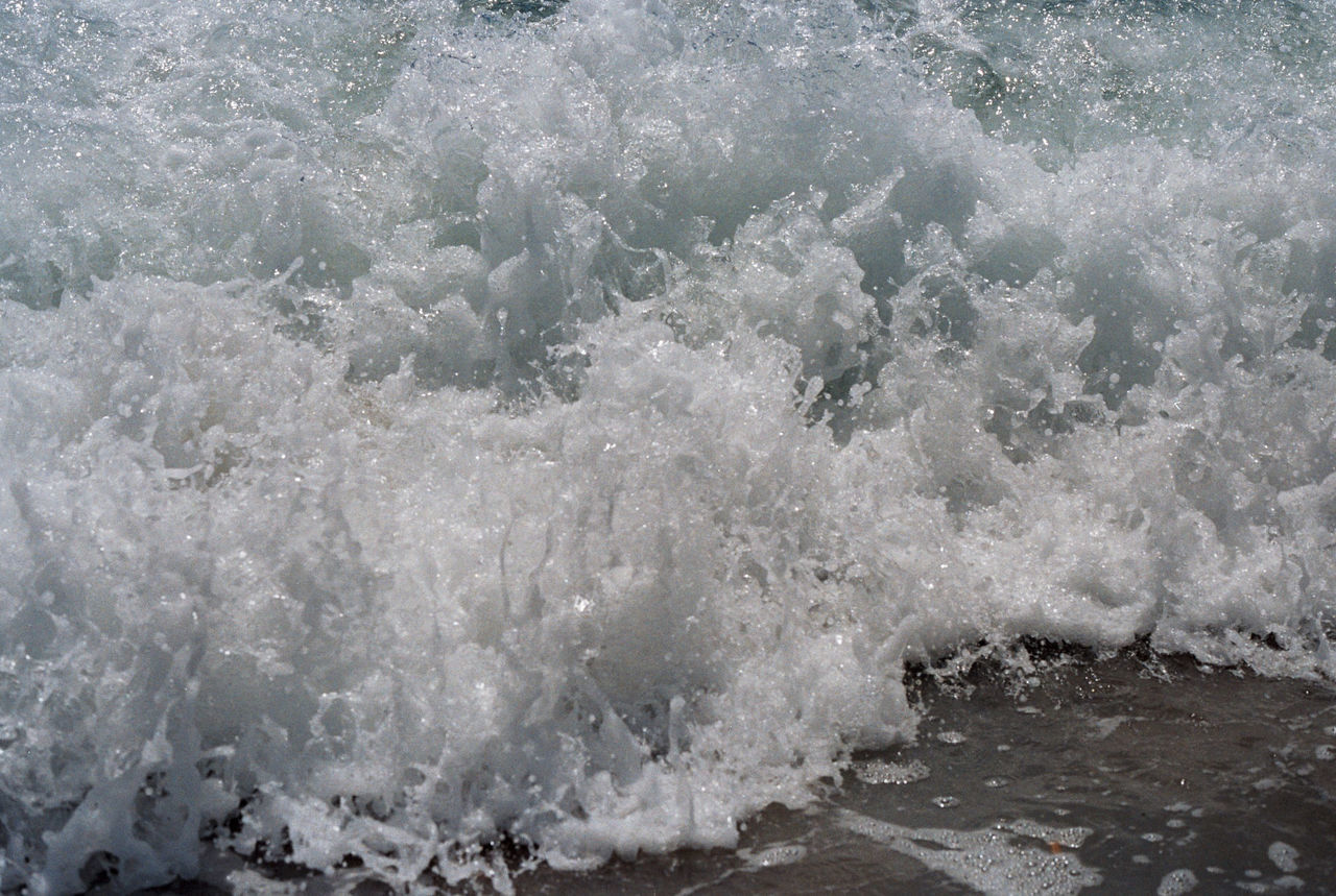 HIGH ANGLE VIEW OF SEA WAVES SPLASHING ON SHORE