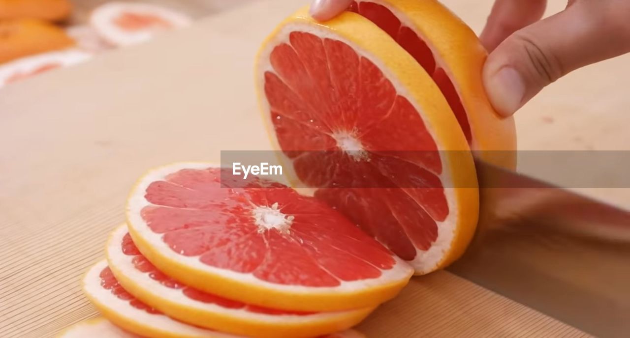 CLOSE-UP OF HAND HOLDING ORANGE