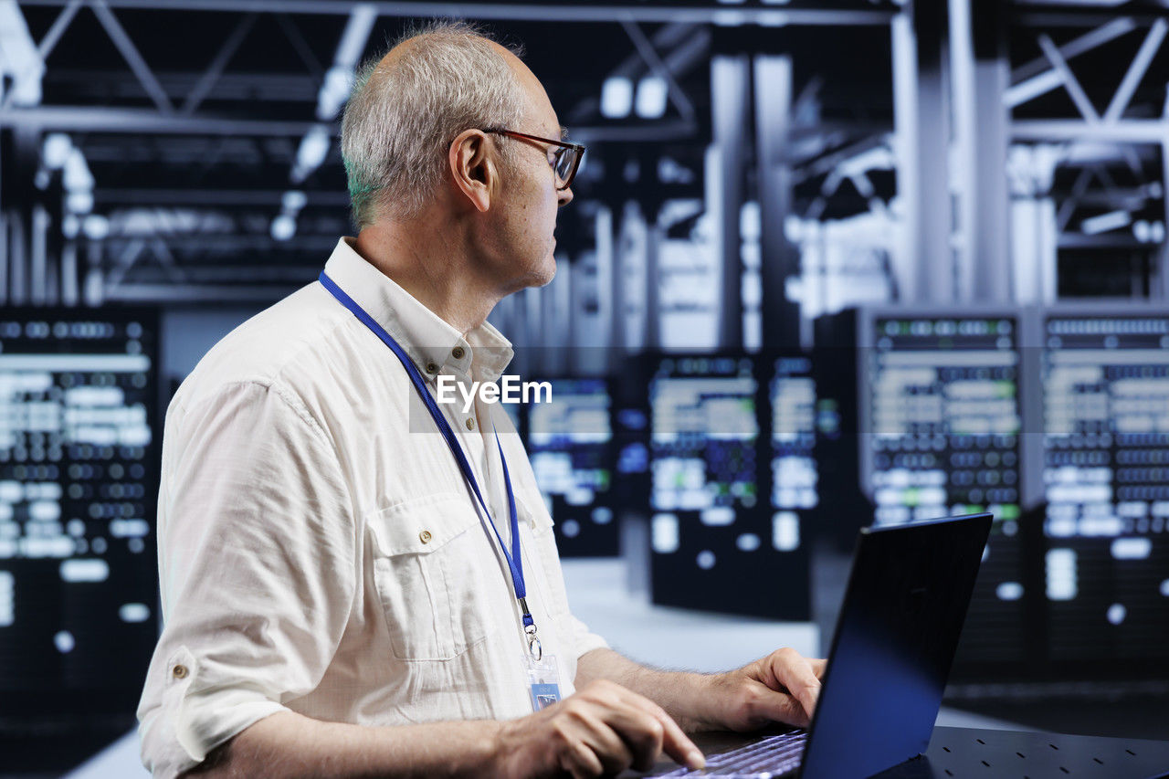 side view of man using laptop while standing in city