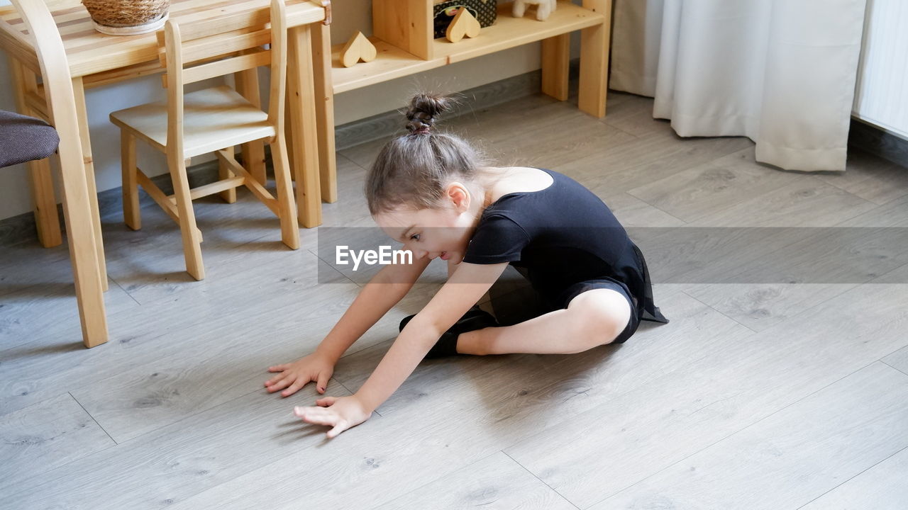 High angle view of girl sitting on hardwood floor at home