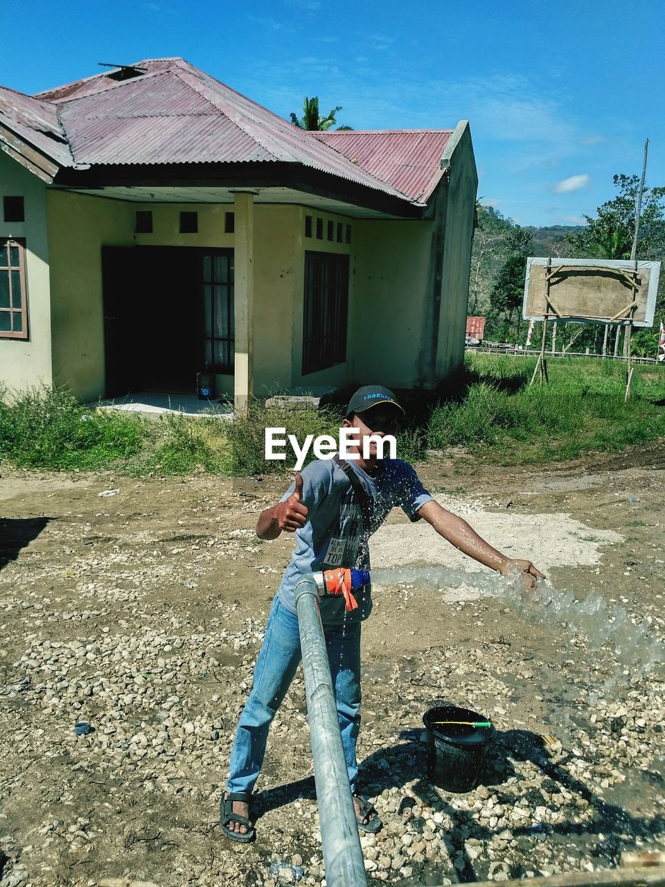 FULL LENGTH OF HAPPY BOY STANDING OUTSIDE HOUSE