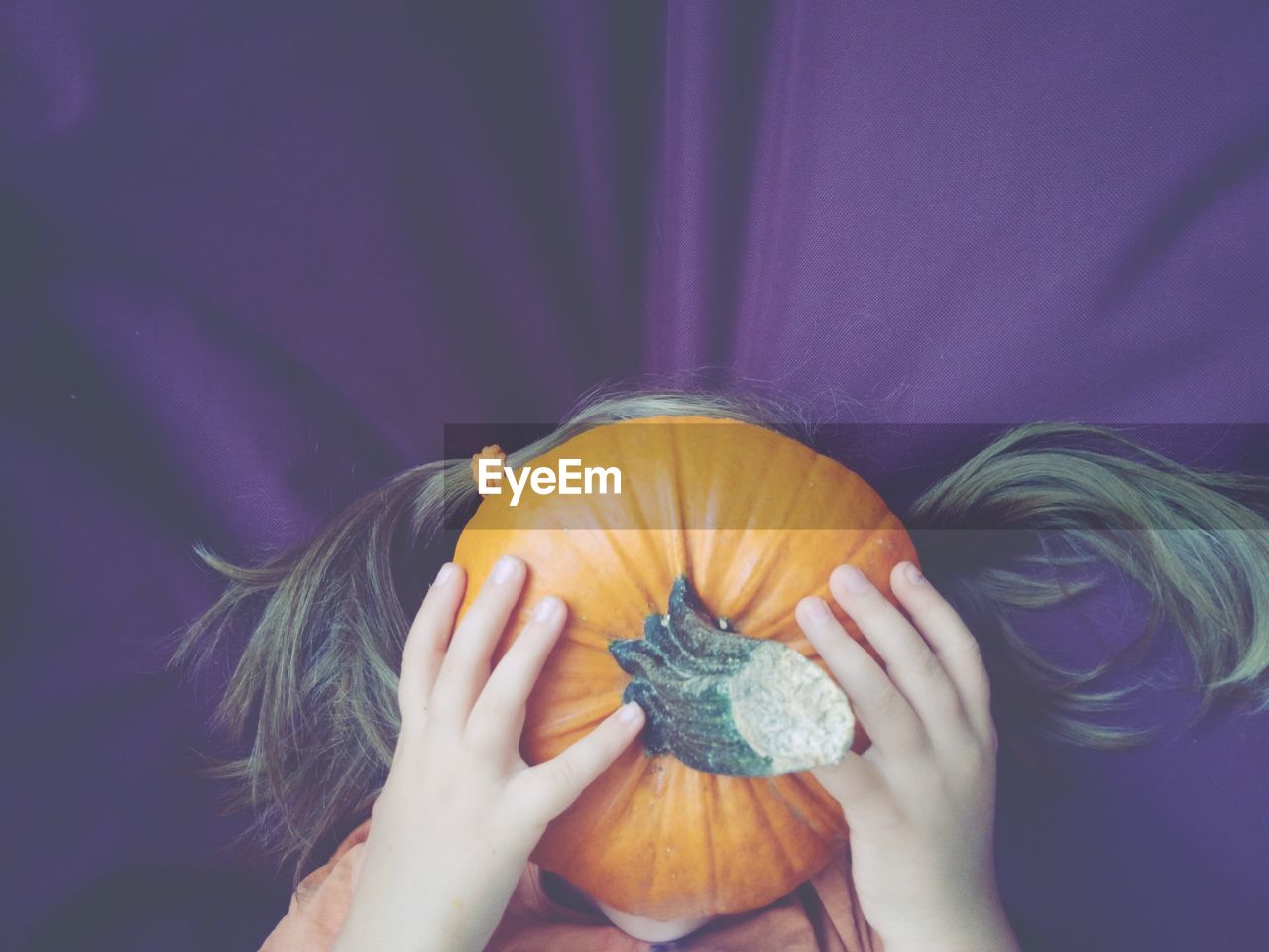 Close-up of girl covering face with pumpkin