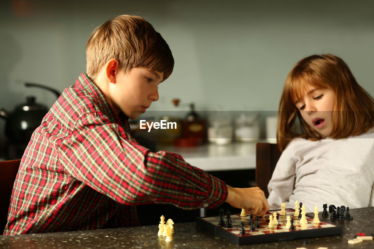 Children playing chess at home kitchen