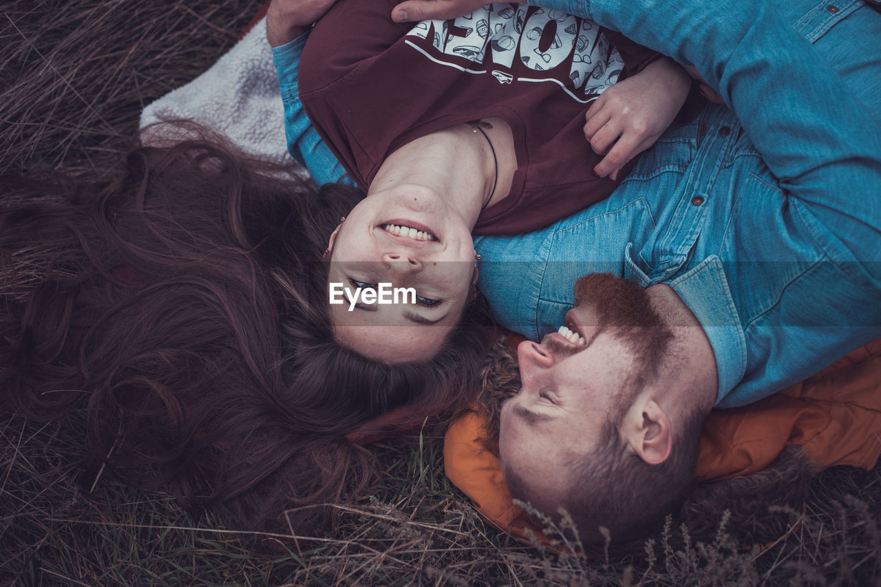 High angle view of couple lying on grass outdoors