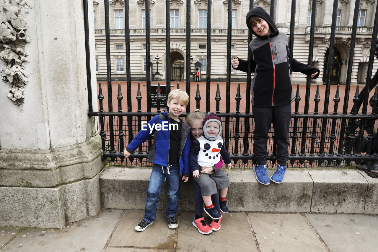 Four siblings sit at the gate of buckingham palace