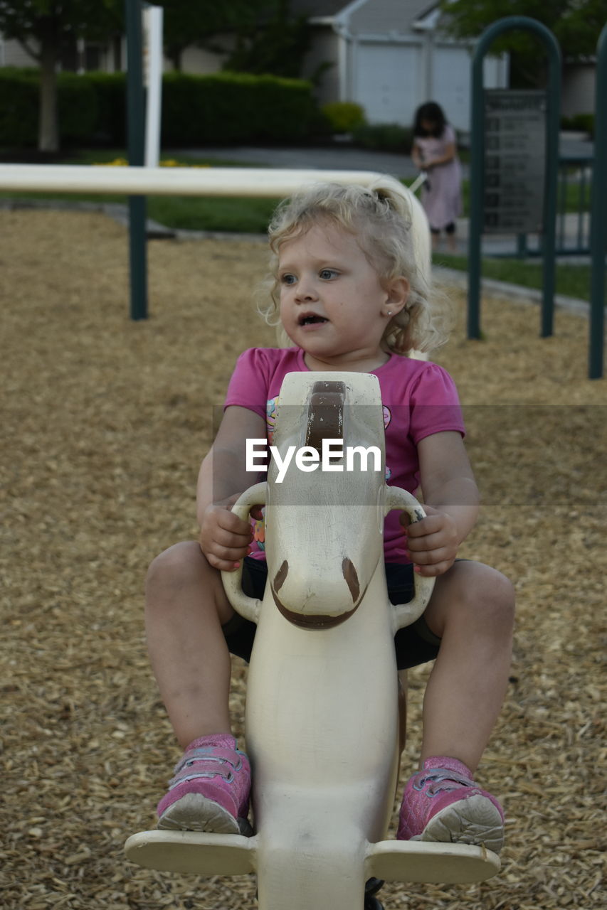 Cute girl sitting on statue in playground