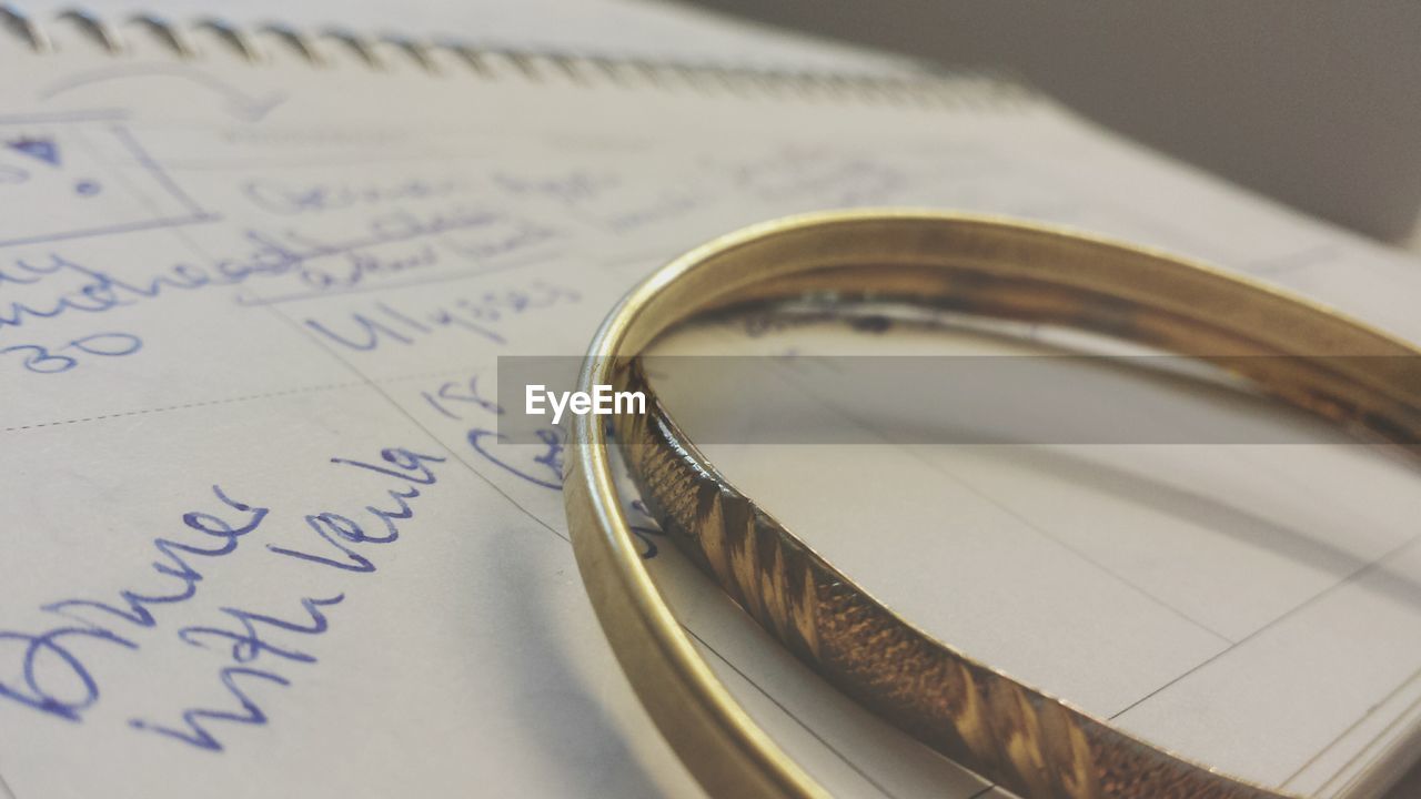 Close-up of gold colored bracelets on open book