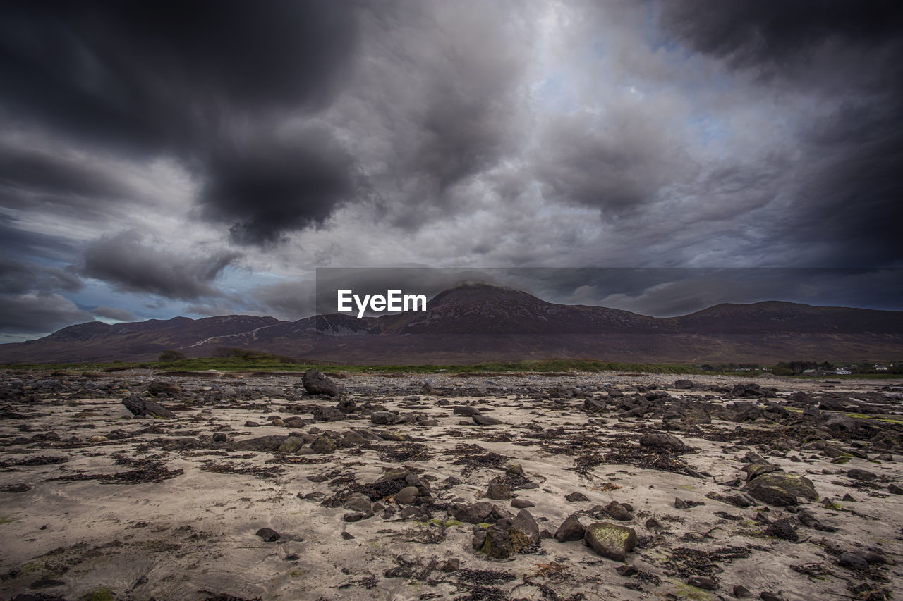 Scenic view of landscape and mountains against storm clouds