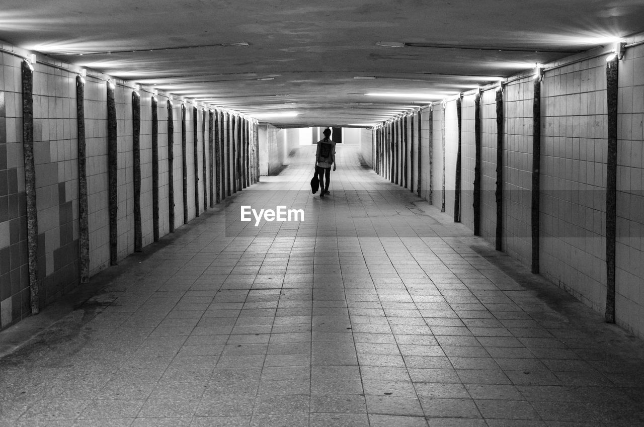 Rear view of man walking in subway tunnel