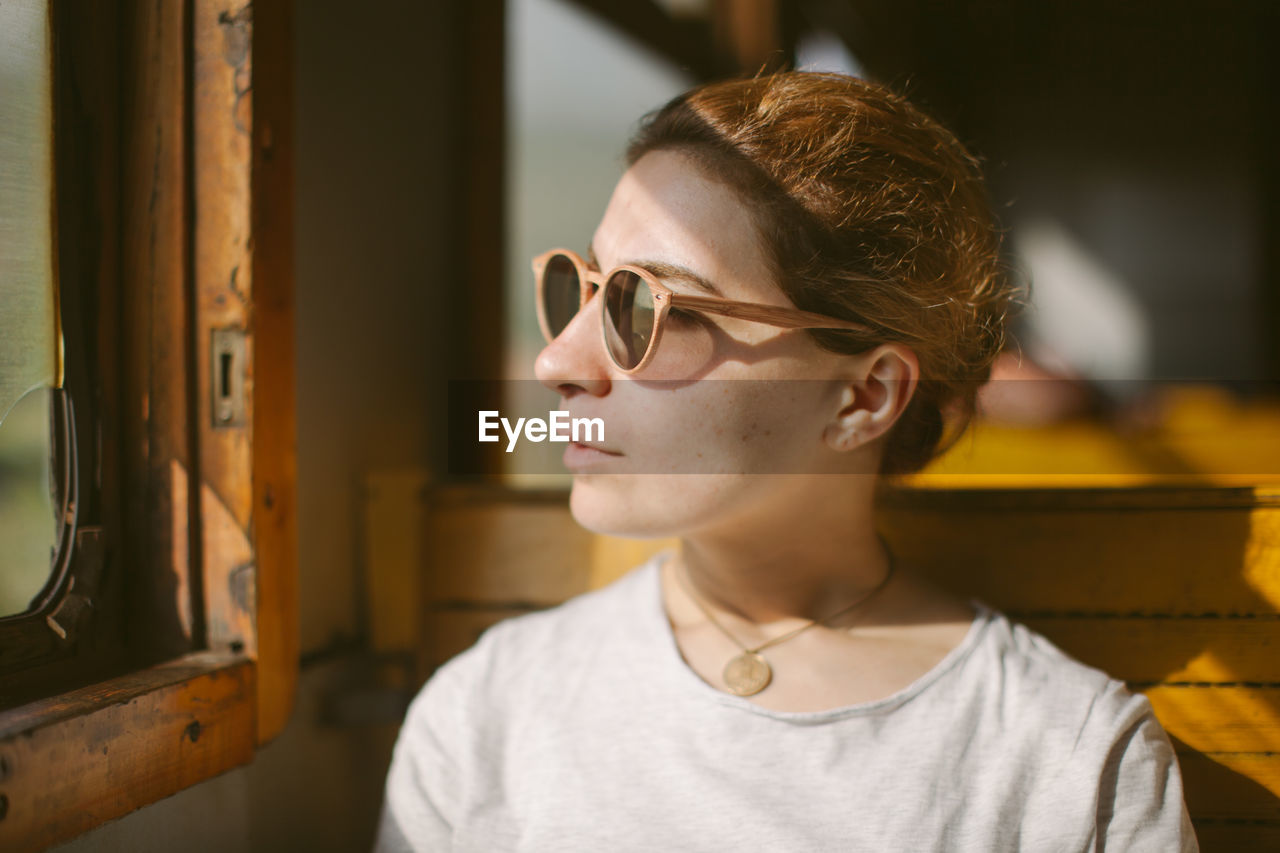 Close-up of young woman wearing sunglasses at home