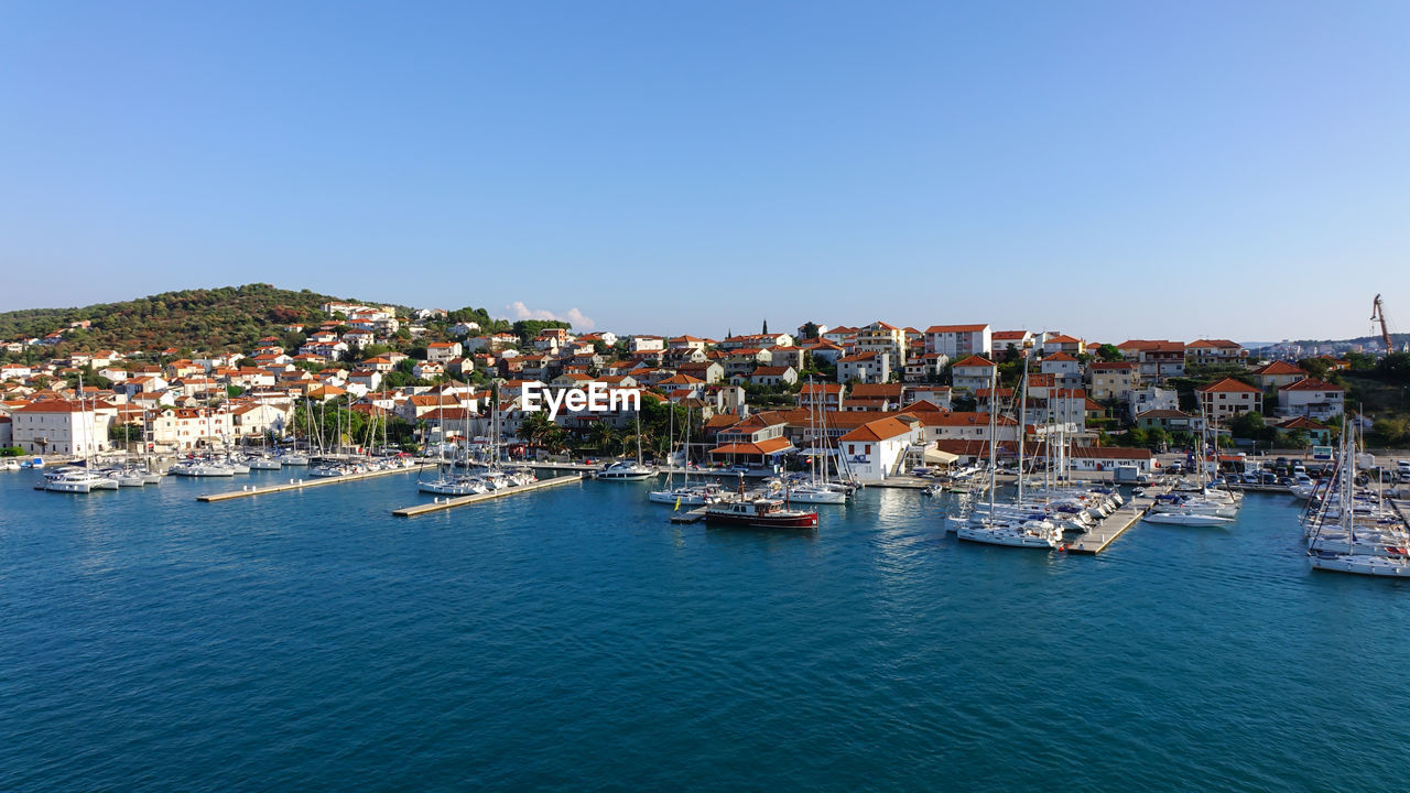 Aerial view of townscape by sea against clear sky