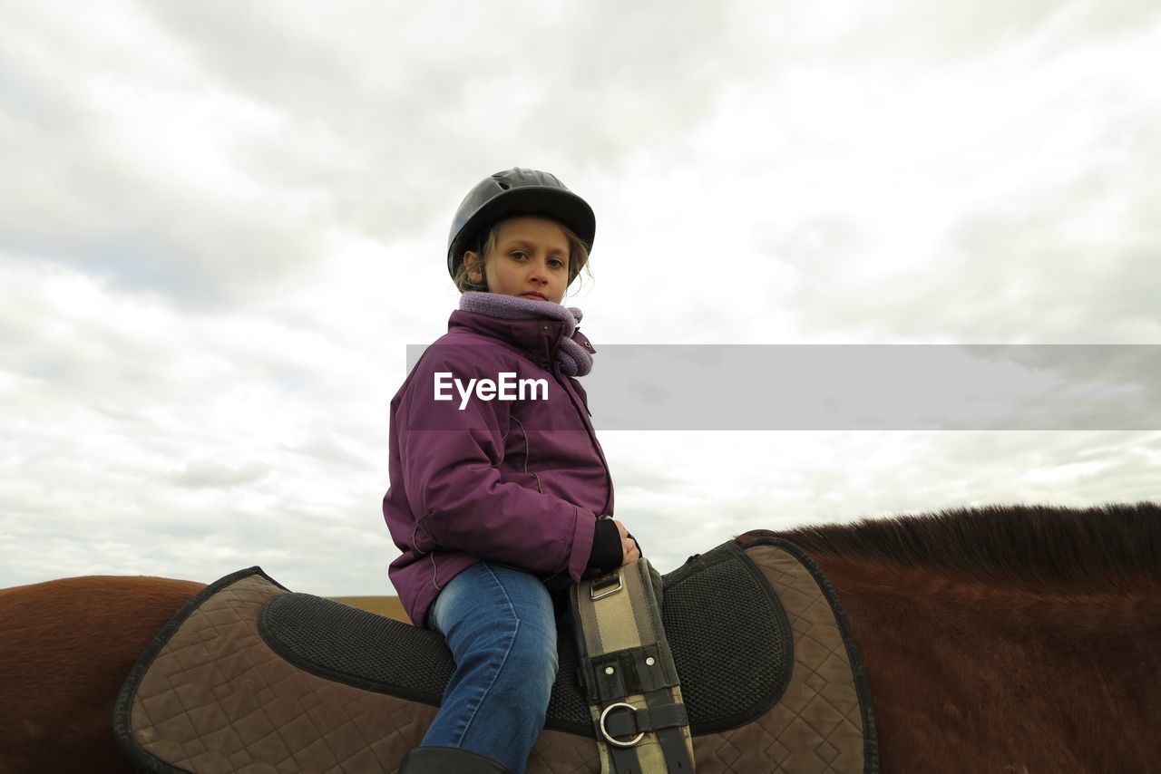 Low angle view of girl riding horse