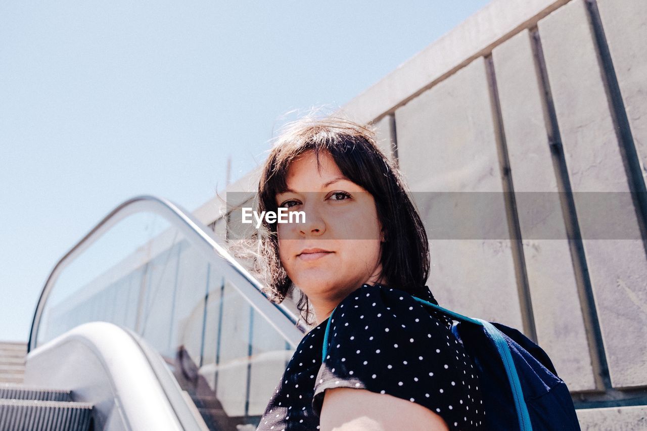 Portrait of woman on escalator against clear sky