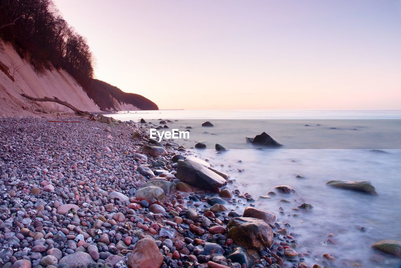 Romantic morning at sea. big boulder in smooth wavy sea. long exposure for smooth dreamy water level