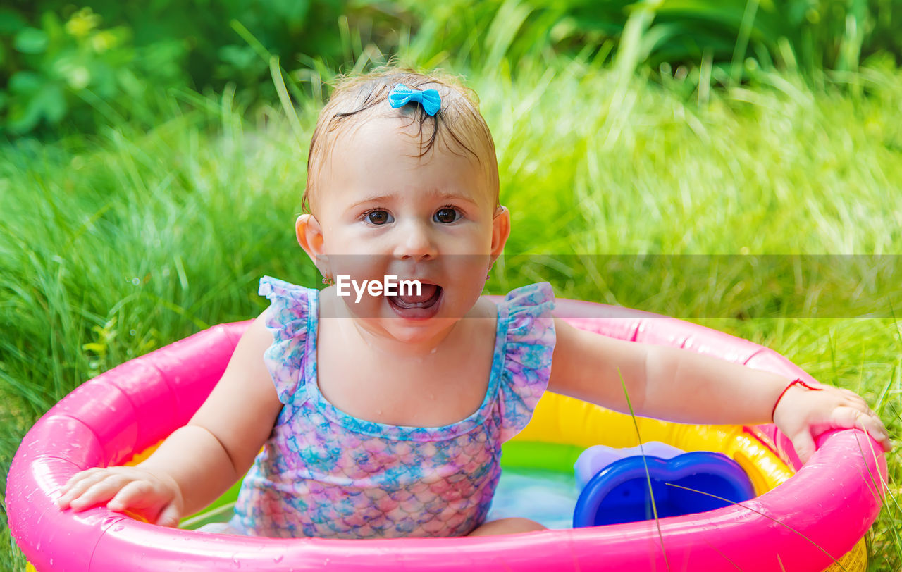 Portrait of smiling cute baby girl sitting in wading pool