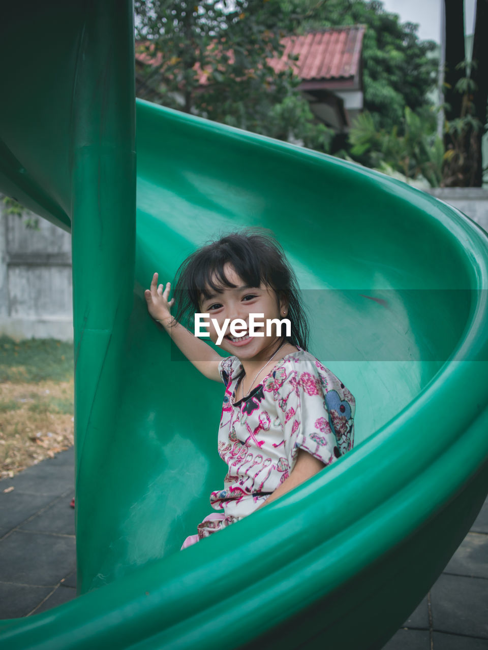 Portrait of cute smiling girl sliding in playground