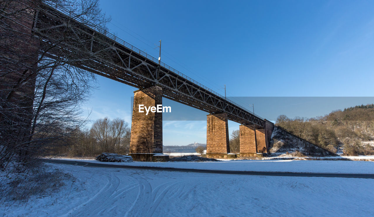 Road by bridge against clear sky during winter