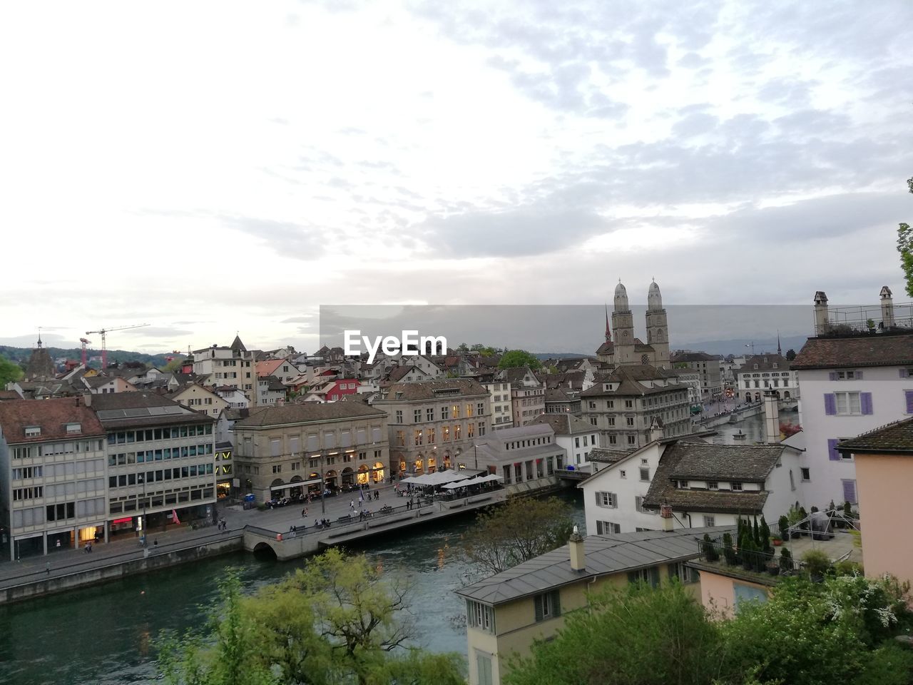 HIGH ANGLE VIEW OF BUILDINGS AND RIVER AGAINST SKY