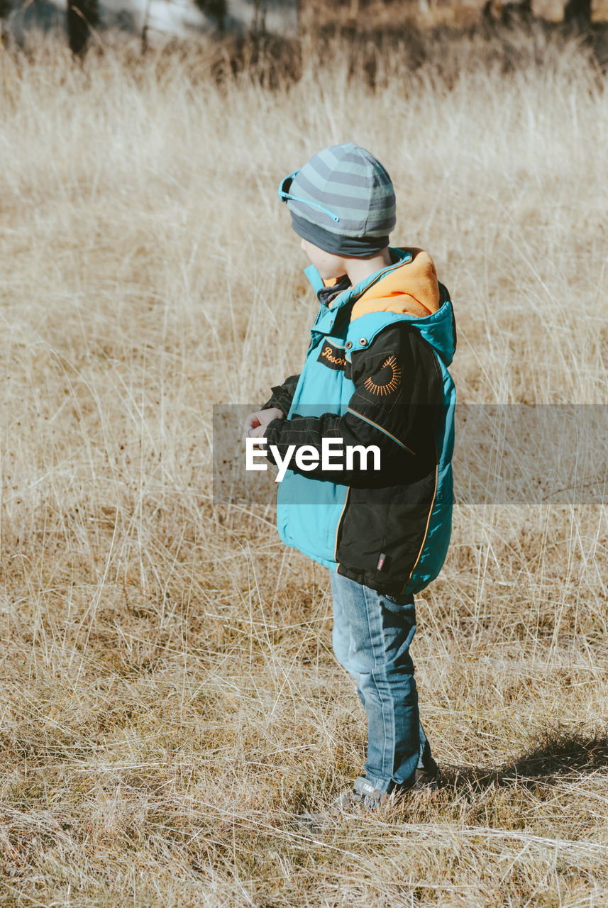 Side view of boy standing on grassy field