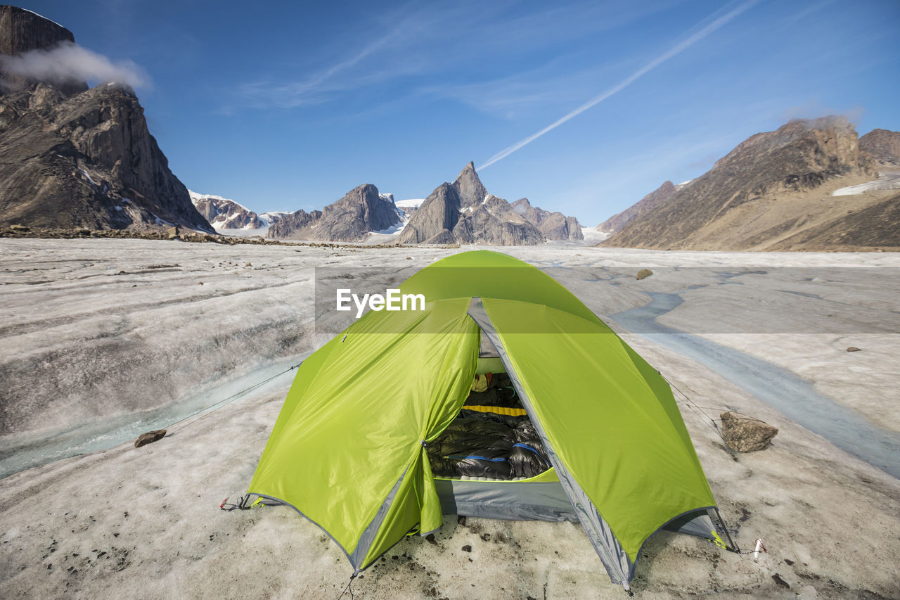 Mountaineering tent set up on glacier below dramatic mountain peaks.