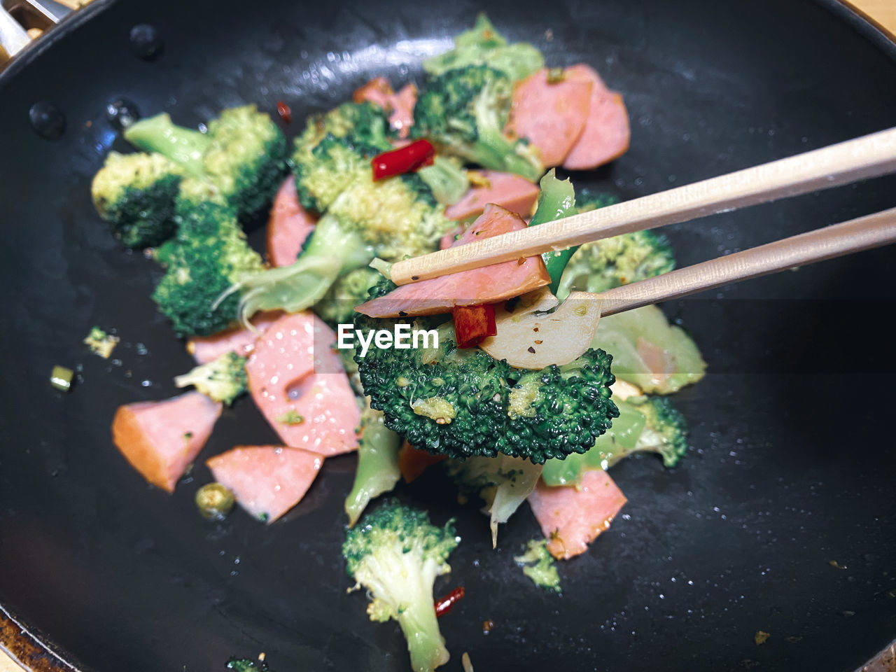 High angle view of food in cooking pan. broccoli , bacon , garlic and red chill peppers 