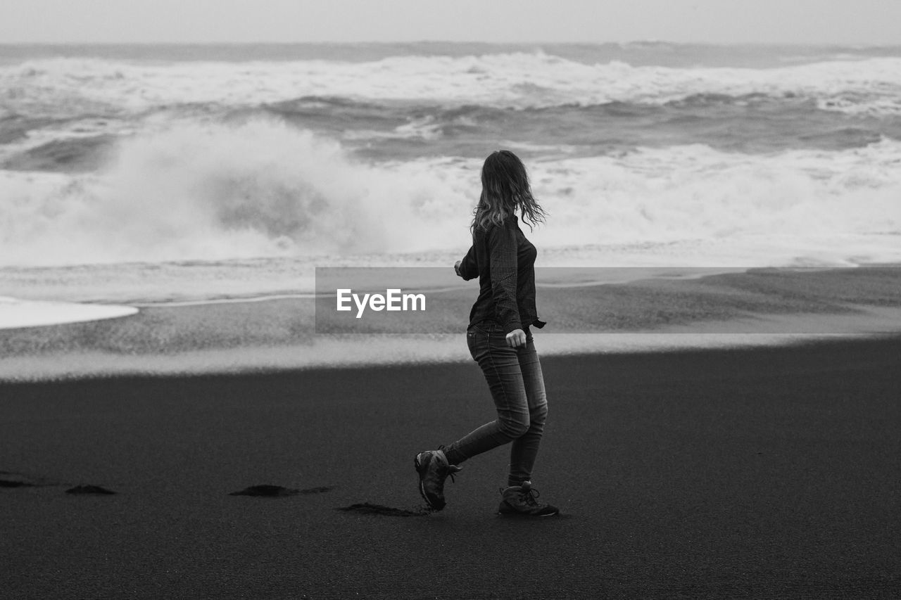 Woman looking at stormy sea on beach monochrome scenic photography