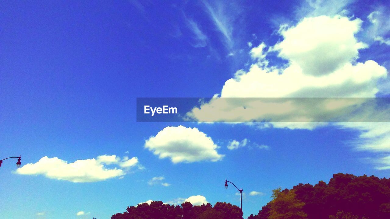 LOW ANGLE VIEW OF BLUE SKY AND CLOUDS IN SUNLIGHT