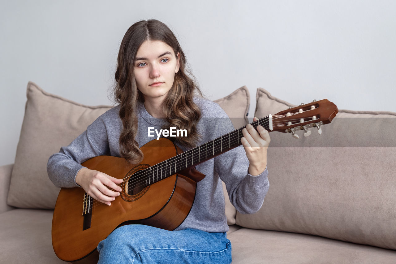 Sad girl playing guitar at home