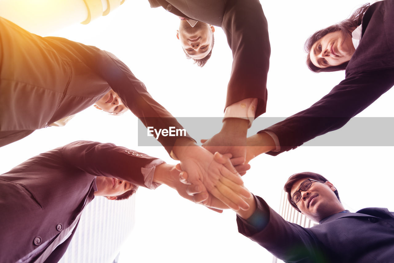 Low angle view of business people huddling against sky