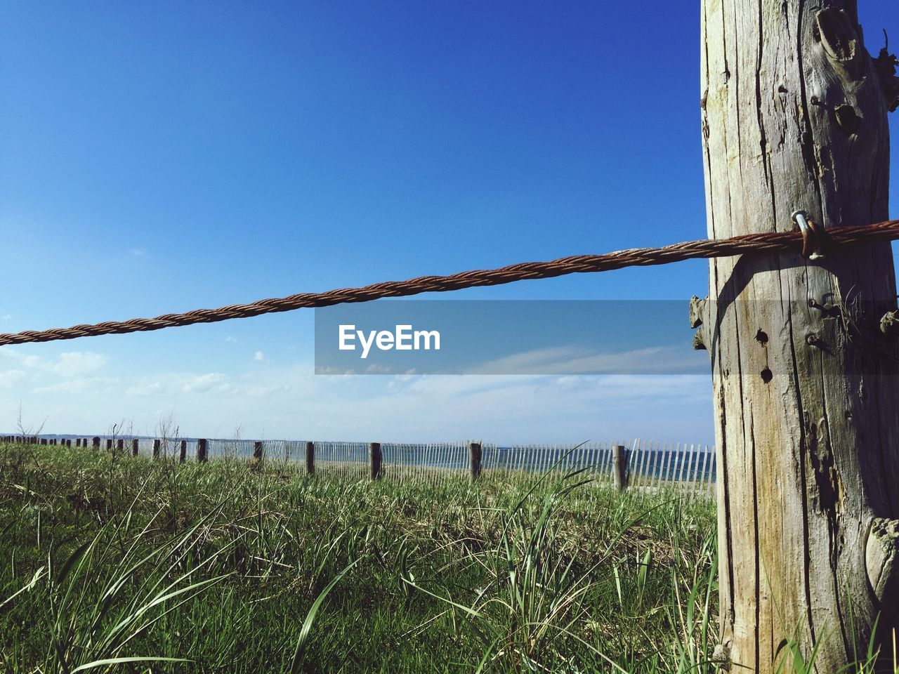 Close-up of wooden post on field against clear sky