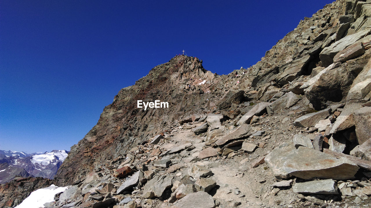 Low angle view of rocky mountains against clear blue sky