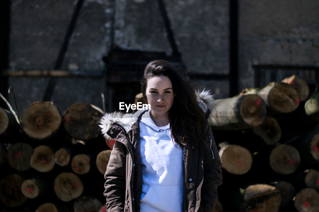 Portrait of smiling young woman standing logs