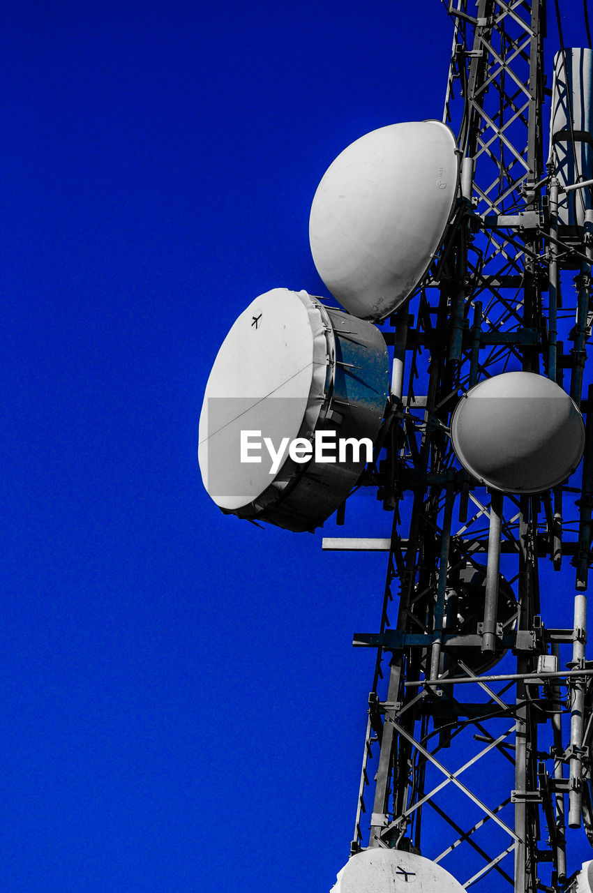 Low angle view of communications tower against blue sky