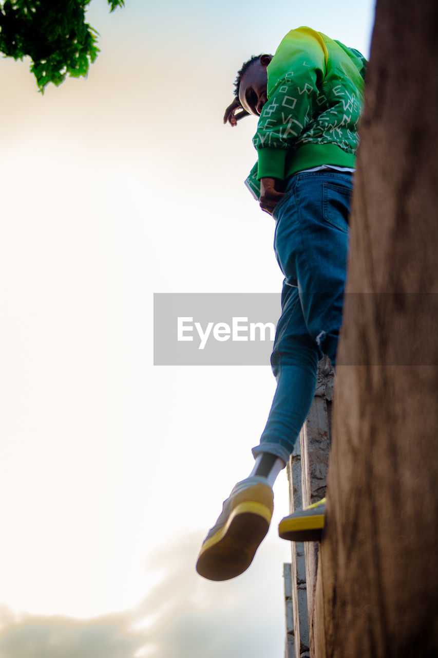 LOW ANGLE VIEW OF BOY WITH ARMS OUTSTRETCHED AGAINST SKY